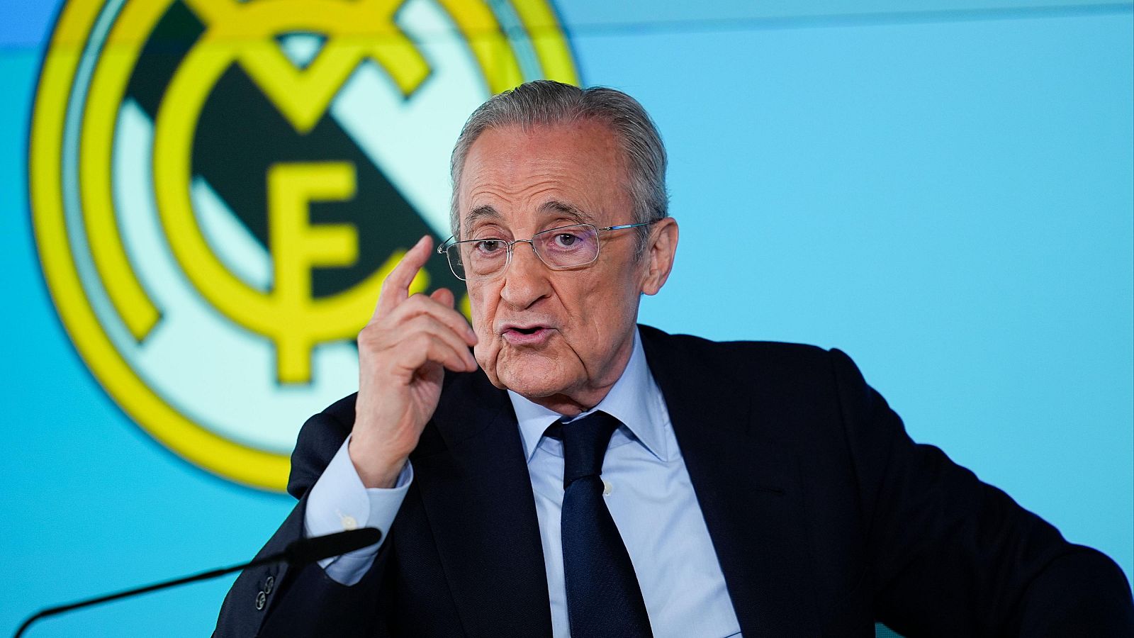 Florentino Pérez, presidente del Real Madrid C.F., habla en una rueda de prensa, con el escudo del club al fondo.