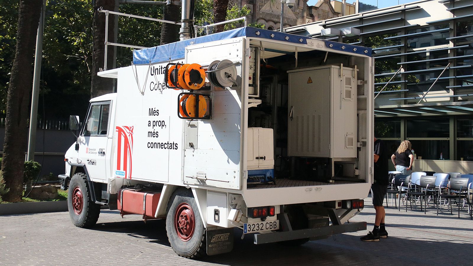 Camíó blanc "Unita Cobertura" del Govern d'Andorra (matrícula 3232 CBB) amb equips de connectivitat, presentat davant edifici modern amb cadires preparades.