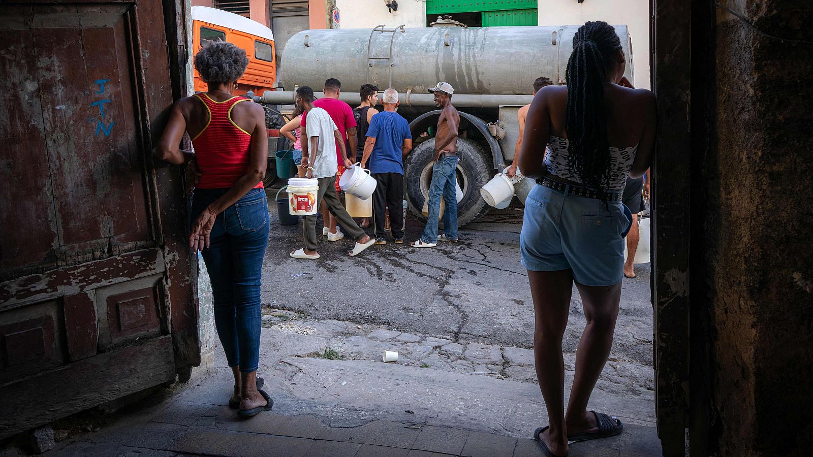 Residentes cargan recipientes mientras hacen cola para obtener agua potable de un camión cisterna en un barrio de Matanzas, Cuba.
