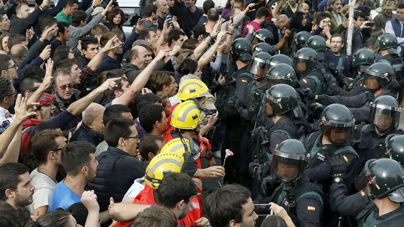 Confrontación entre manifestantes civiles y la Guardia Civil en una calle urbana. Una persona ofrece una flor rosa en medio de la tensión.