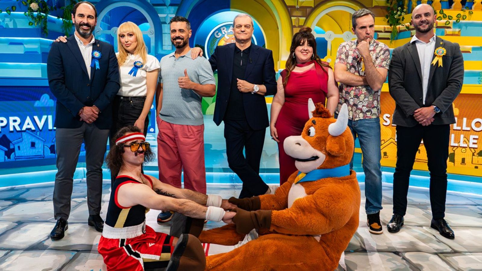 Plató de "Grand Prix del Verano" con Ramón García, Michelle Calvó, Cristinini, equipo azul y amarillo, y Wilbur interactuando con La Vaquilla. Se lee "GRAN PRIX" en el fondo.