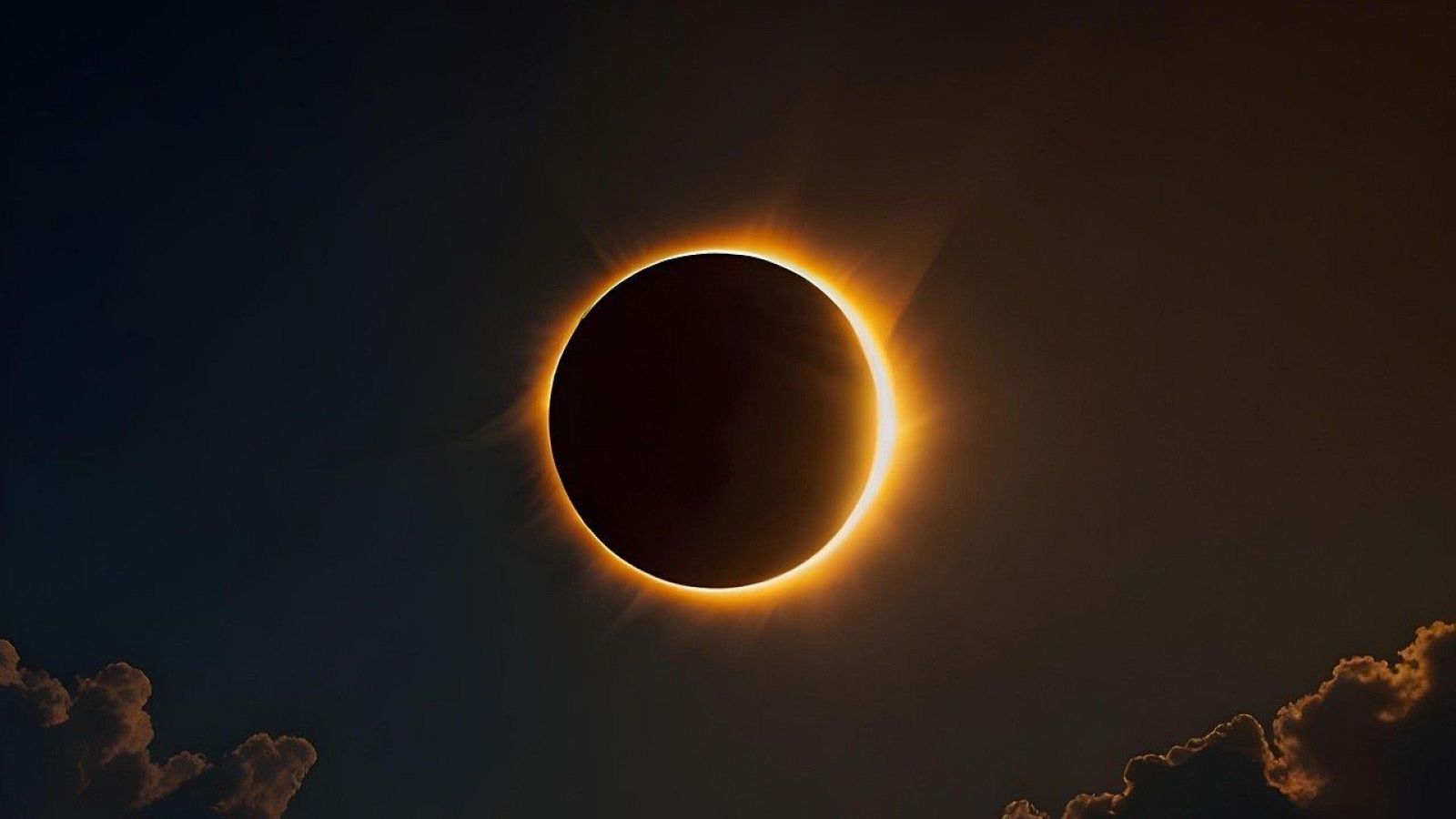 Eclipse solar total con corona radiante y nubes iluminadas en un cielo oscuro.