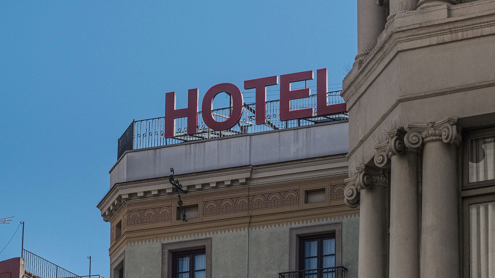 Edificio clásico con letrero "HOTEL" en rojo sobre fondo de cielo azul.