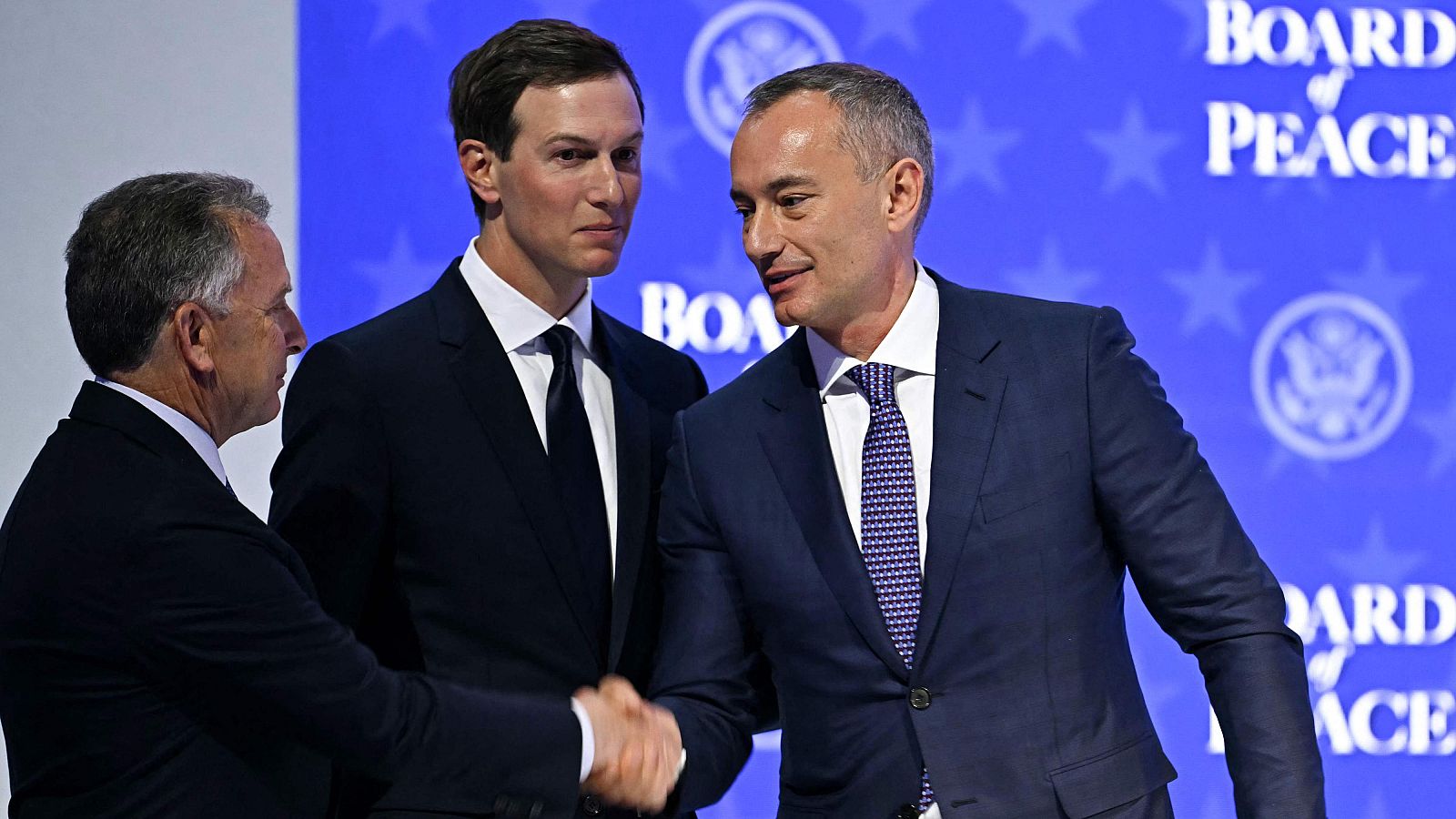 Jared Kushner, Steve Witkoff y Nickolay Mladenov en un evento diplomático con el lema "BOARD of PEACE" y un fondo estrellado.