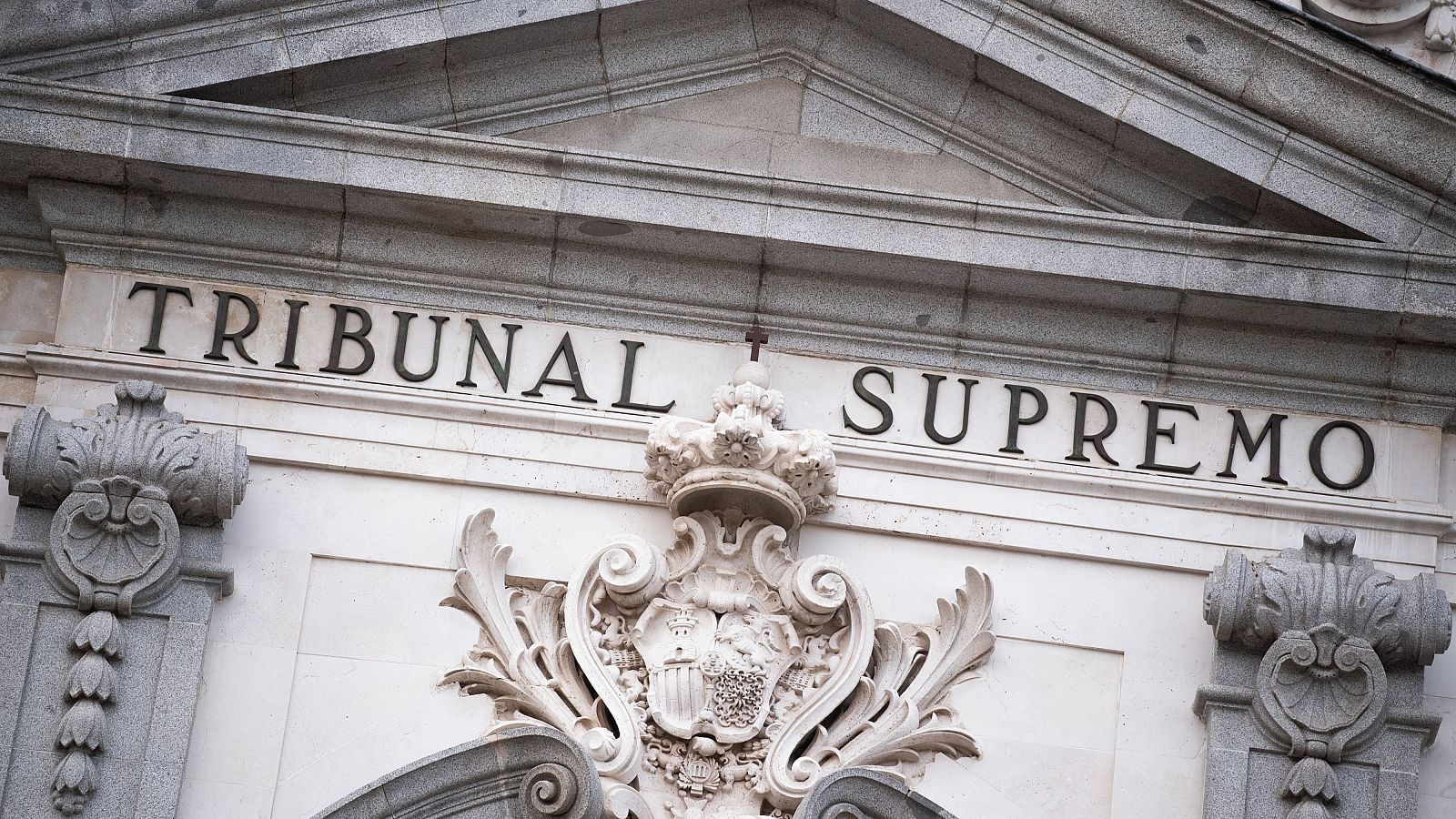 Fachada del Tribunal Supremo con el nombre tallado y escudo real español, arquitectura clásica en piedra clara.