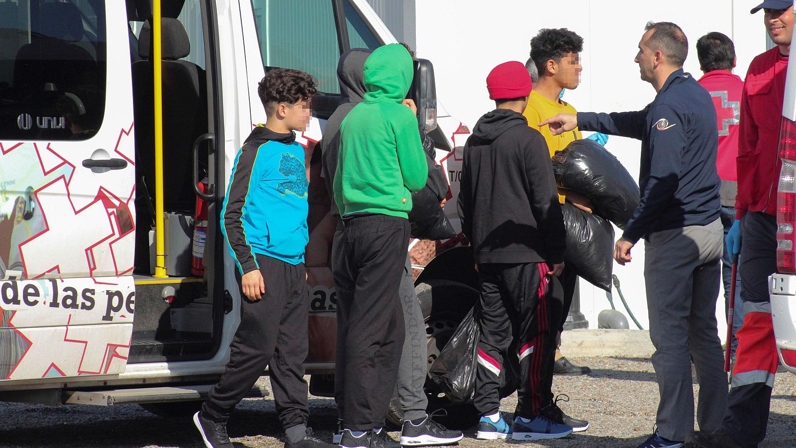 Varios menores extranjeros no acompañados, acompañados por voluntarios de la Cruz Roja, son trasladados a un albergue provisional en una imagen de archivo de 2020.
