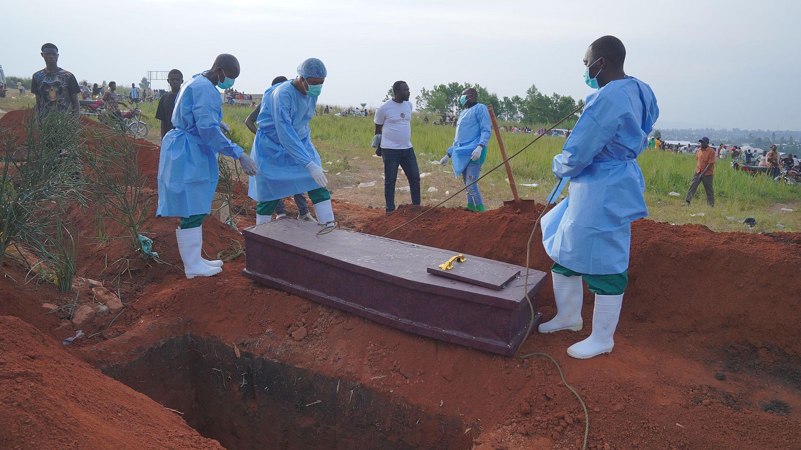 Personas con equipo de protección se preparan para bajar a una fosa el ataúd con los restos de Baudjo Baraka Jules, un niño de seis años fallecido a causa del ébola, en Bunia, provincia de Ituri, en el este del Congo