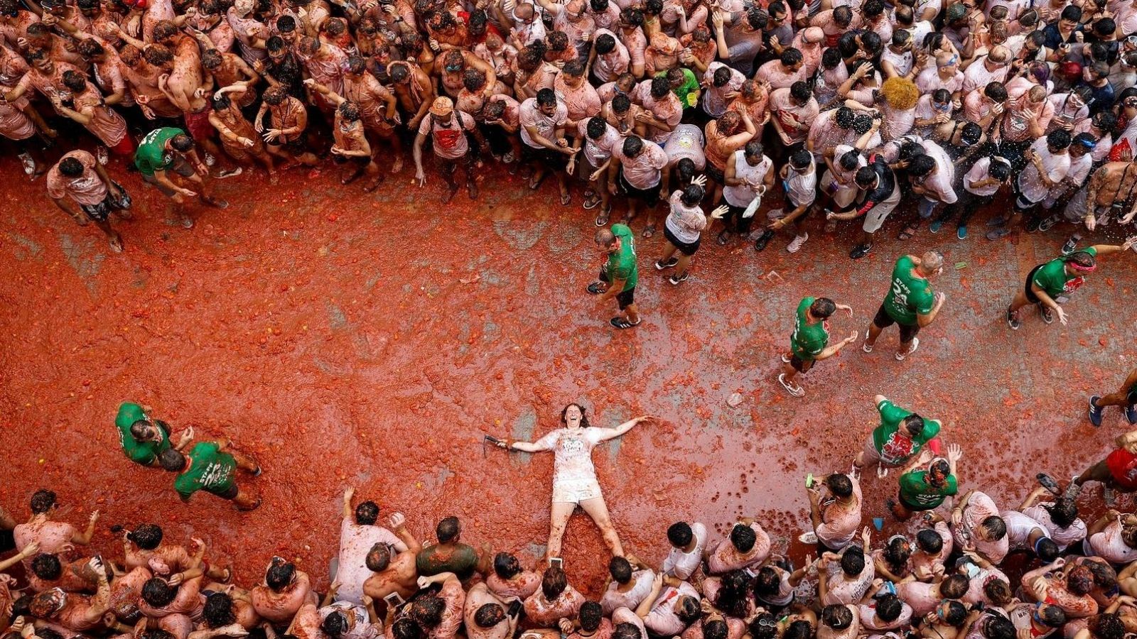 Festival multitudinario con miles de personas inmersas en una marea de pulpa de tomate, cubiertas de rojo y disfrutando de la celebración.