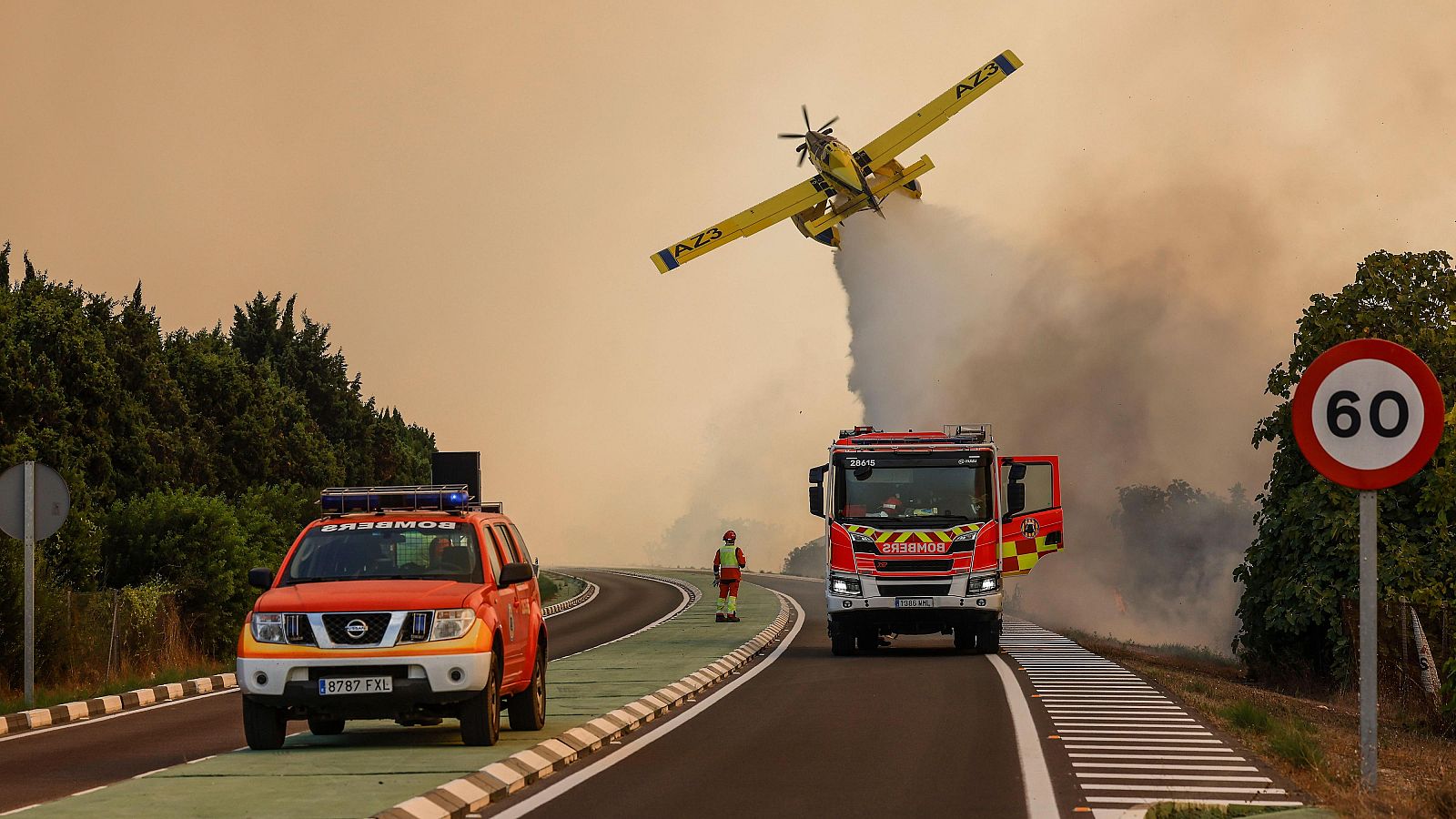 Un avión y coches de bomberos durante las labores de extinción de un incendio forestal