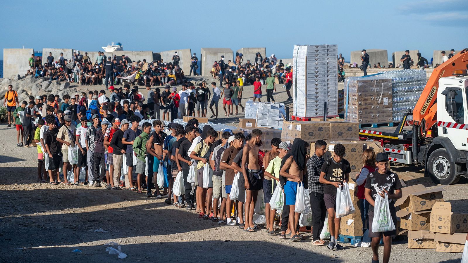 Migrantes hacen cola para recibir ayuda humanitaria, a 27 de agosto de 2026, en Ceuta