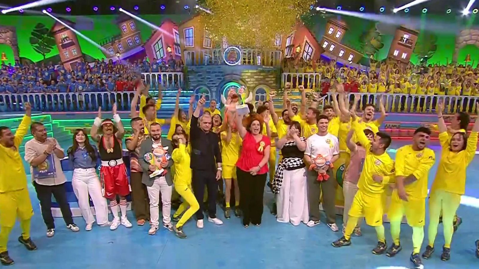 Celebración de la victoria de Quintanar del Rey en el "Grand Prix" con Ramón García y Cristina Pedroche. Confeti dorado cae sobre el escenario mientras el equipo levanta el trofeo.