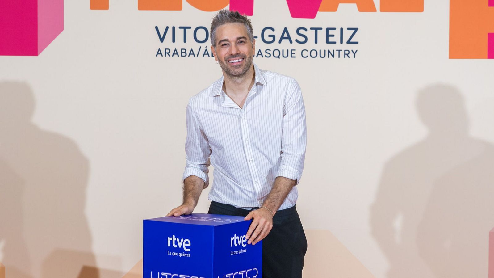 Dani Martínez sonríe apoyado en un cubo azul con logo de RTVE, en un evento en Vitoria-Gasteiz.