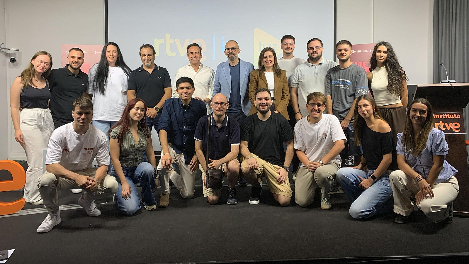 Grupo de veinte personas, incluyendo periodistas y directivos de RTVE, posan sonrientes frente al logo de "rtve" y el "Instituto rtve".