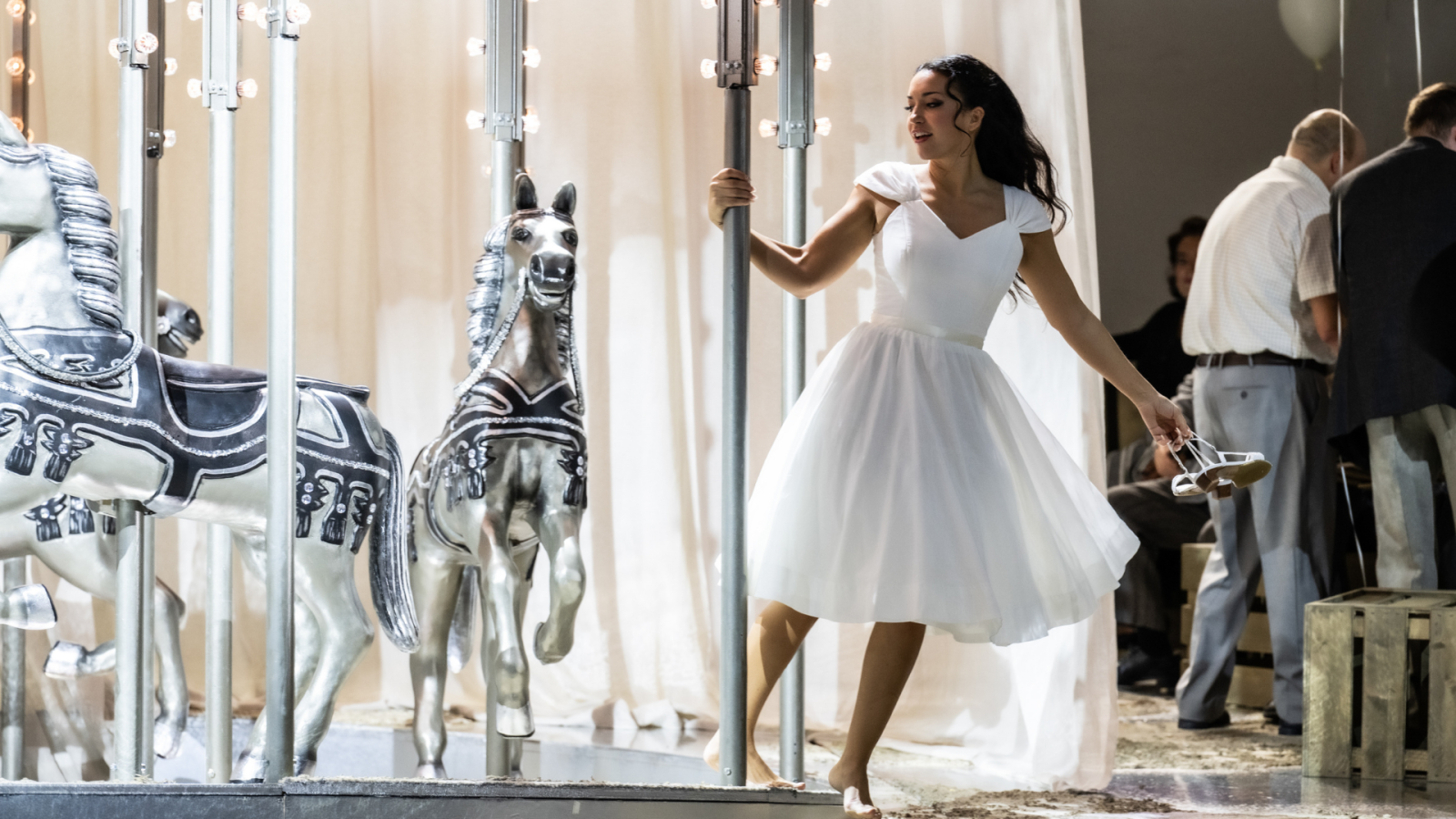 Manon Lescaut con un vestido blanco gira en un carrusel