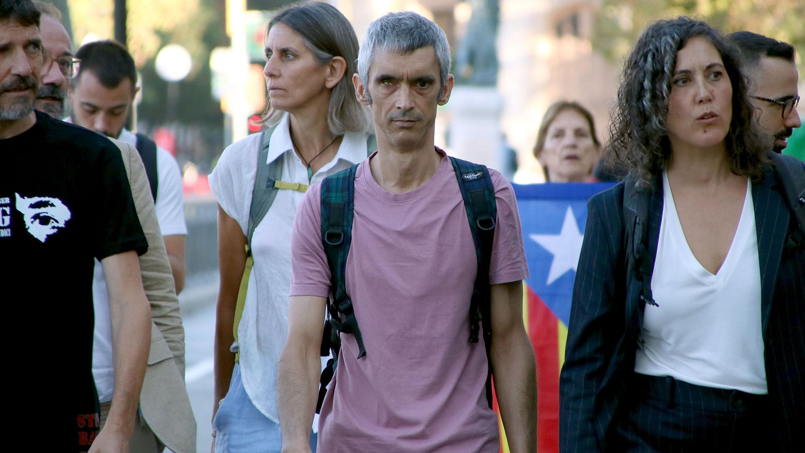 Jordi Cuixart y Dolors Feliu, con una Estelada al fondo, participan en una concentración en un día soleado.