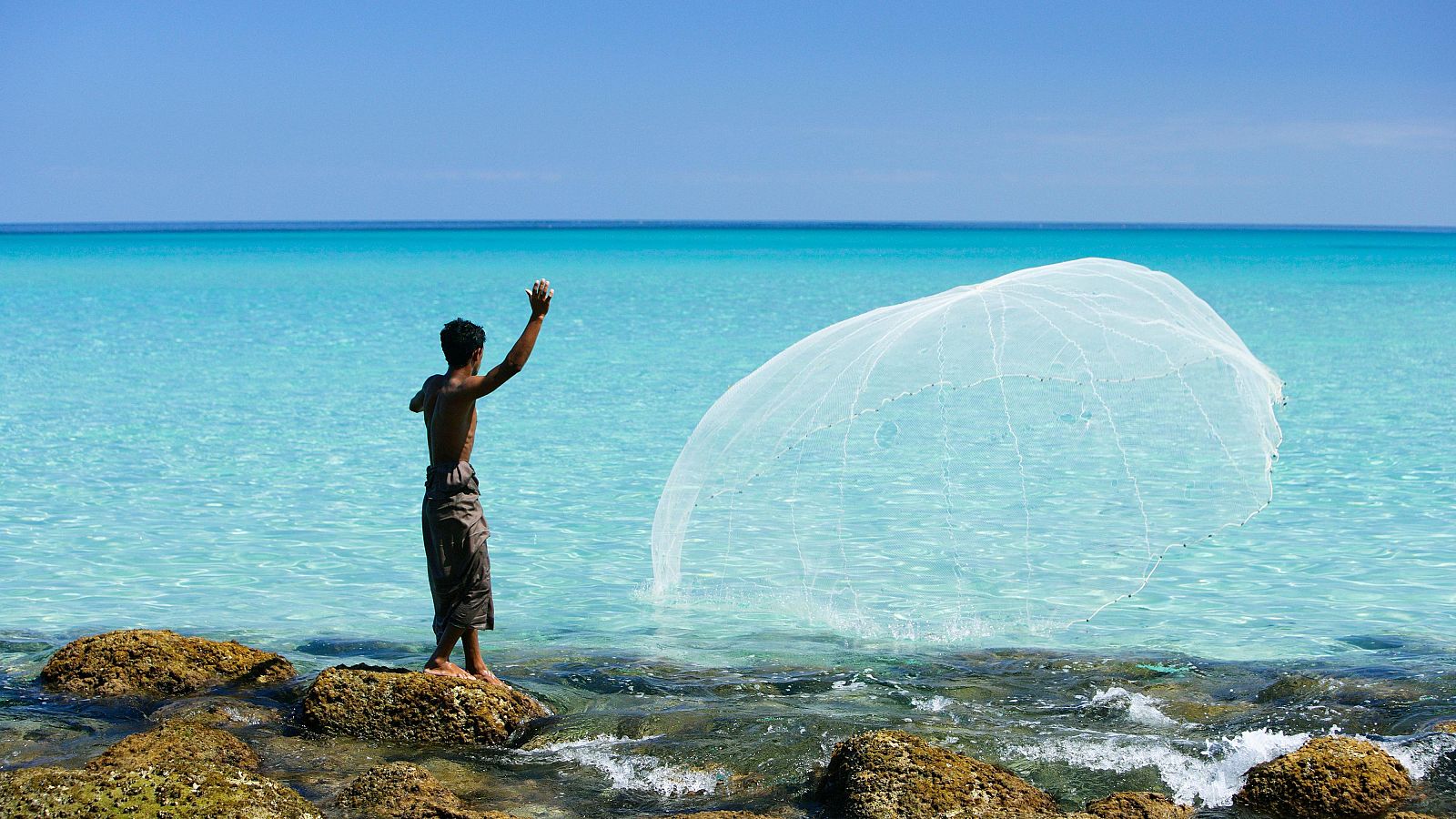Joven somalí lanza la red de pesca en aguas del Océano Índico