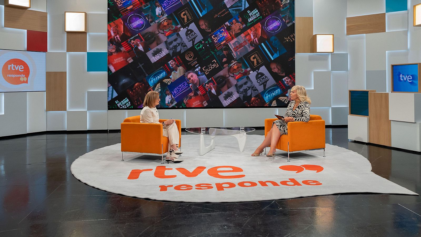 Elena Sánchez Caballero, presentadora de "RTVE Responde", en un plató con pantallas que muestran logos de RTVE y títulos de programas como "HIPSTER" y "THE FLOOR".