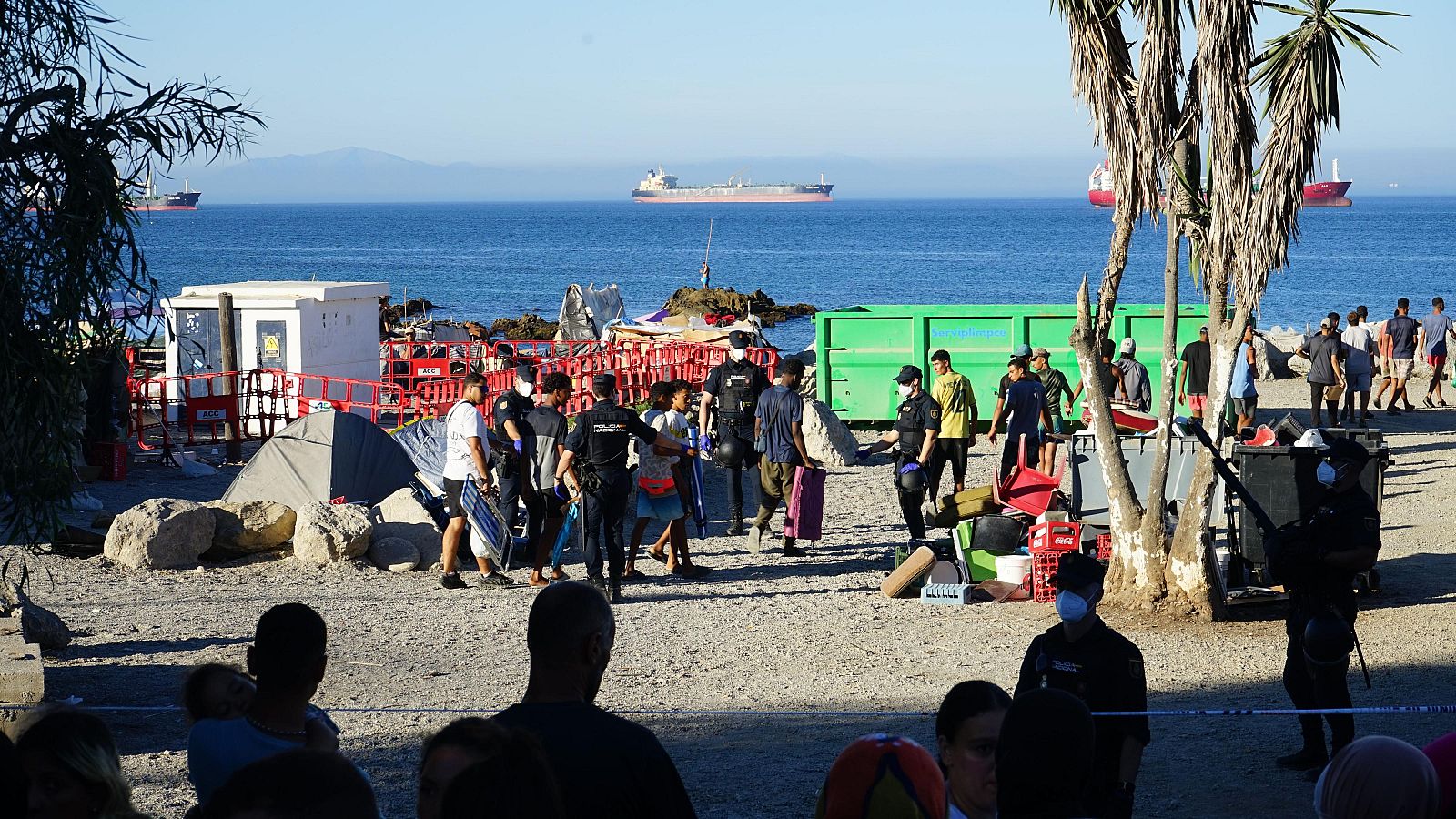Un grupo de personas migrantes acude a recoger la comida que ofrece Cruz Roja en la playa del Trampolín de Ceuta