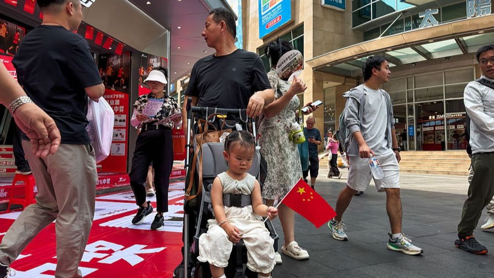 Una niña sostiene una bandera china en una calle comercial de Pekín el 1 de octubre.