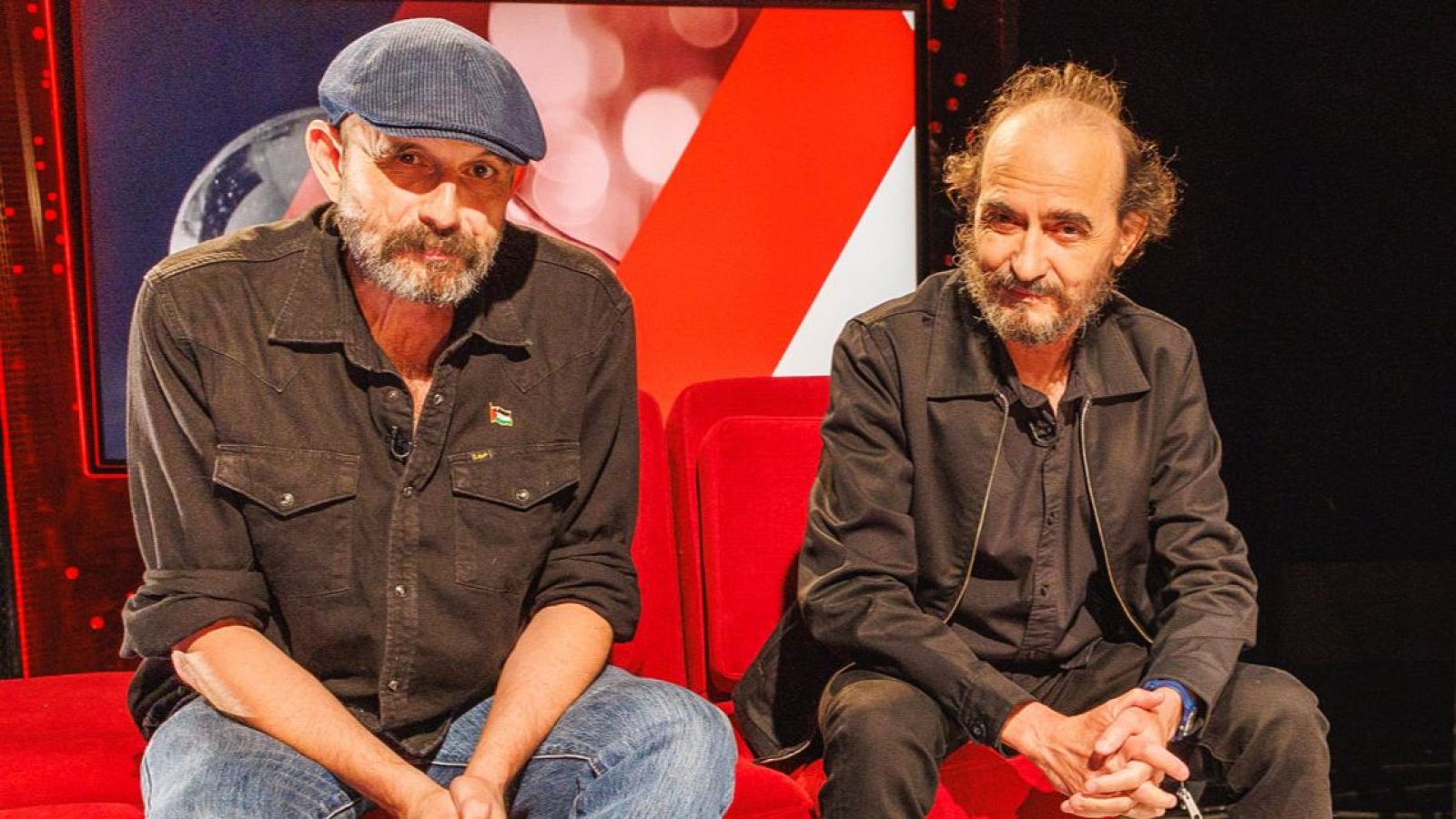 Los músicos Fino Oyonarte y Josele Santiago, del grupo Los Enemigos, sentados en un sofá rojo en el plató del programa cultural Atención Obras.