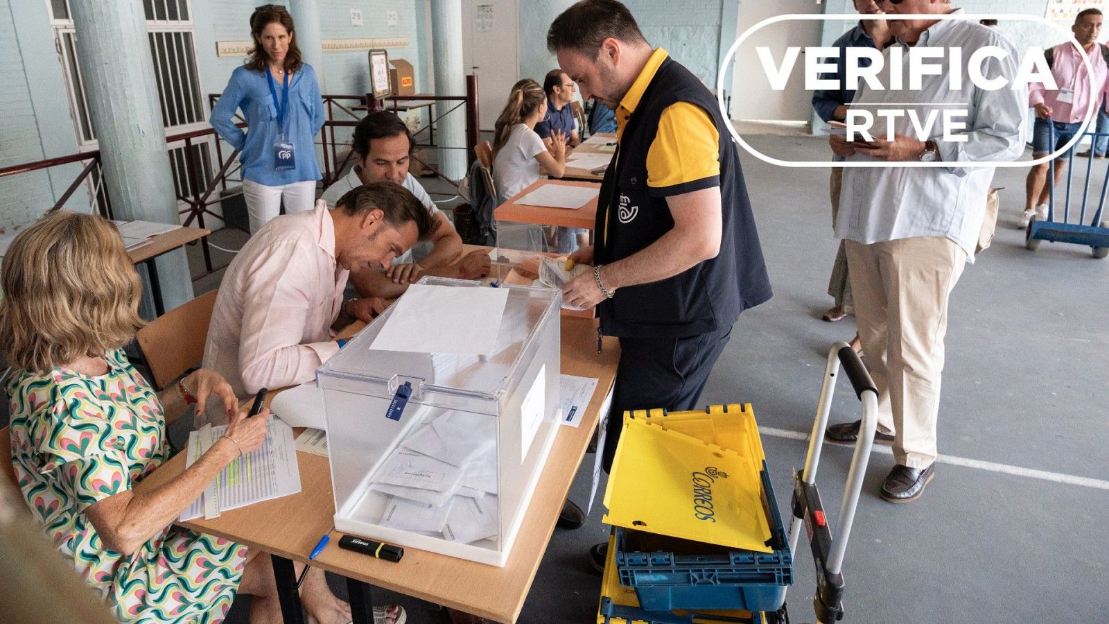 Un cartero en un colegio electoral de Madrid con votos por correo en las elecciones generales de 2023 con el sello VerificaRTVE