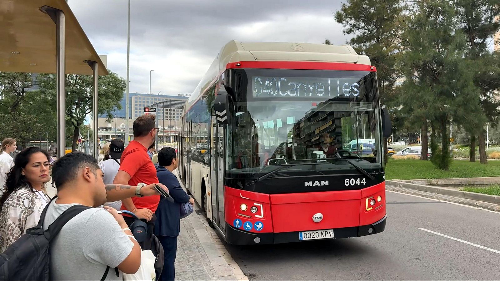 Un autobús urbà de TMB s'atura a una parada a prop de l'estació de Sants, mentre diversos usuaris esperen per pujar-hi.