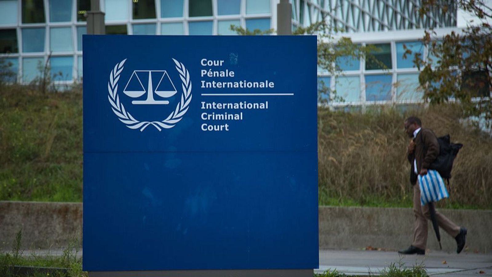 Un hombre pasa junto al cartel de la Corte Penal Internacional en La Haya, Países Bajos