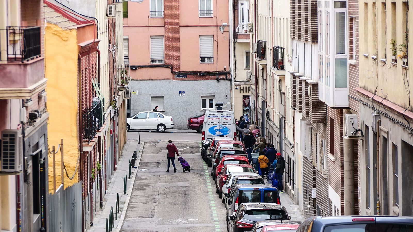 Una calle con viviendas y gente esperando una cola de alimentos en Madrid ilustran el 16º Informe sobre pobreza y desigualdad territorial de EAPN 2026