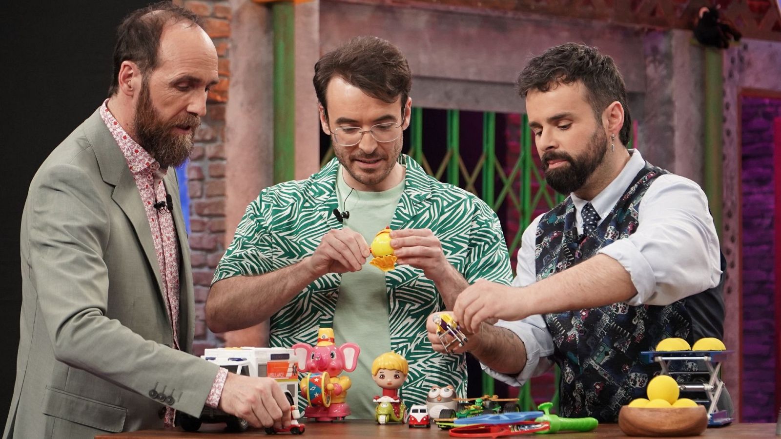 Eduardo Sáenz de Cabezón y dos colaboradores analizan varios juguetes mecánicos y tradicionales sobre una mesa de laboratorio en el plató de un programa de ciencia.