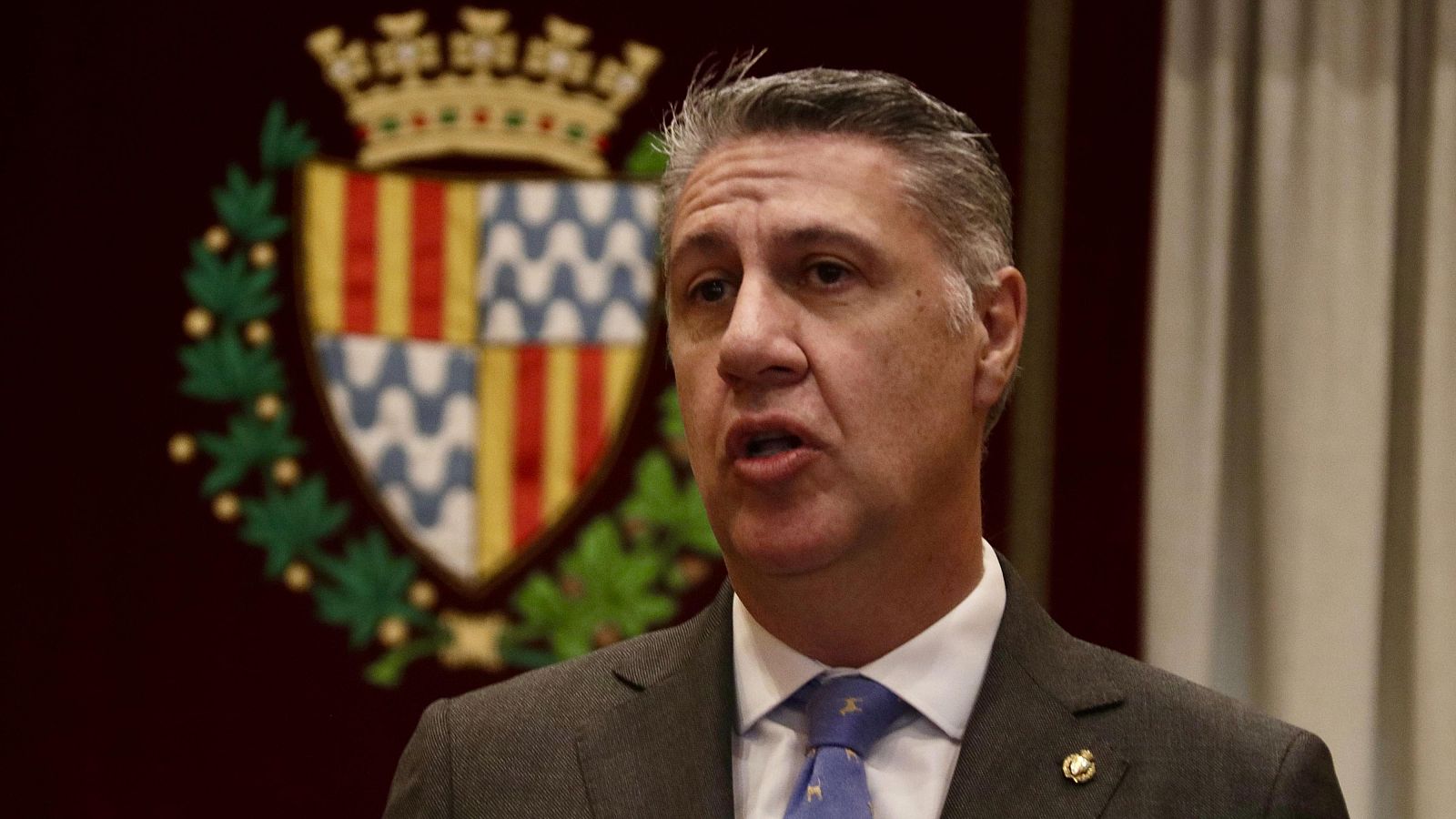 L'alcalde de Badalona, Xavier García Albiol, compareix amb vestit formal davant l'escut de la ciutat.
