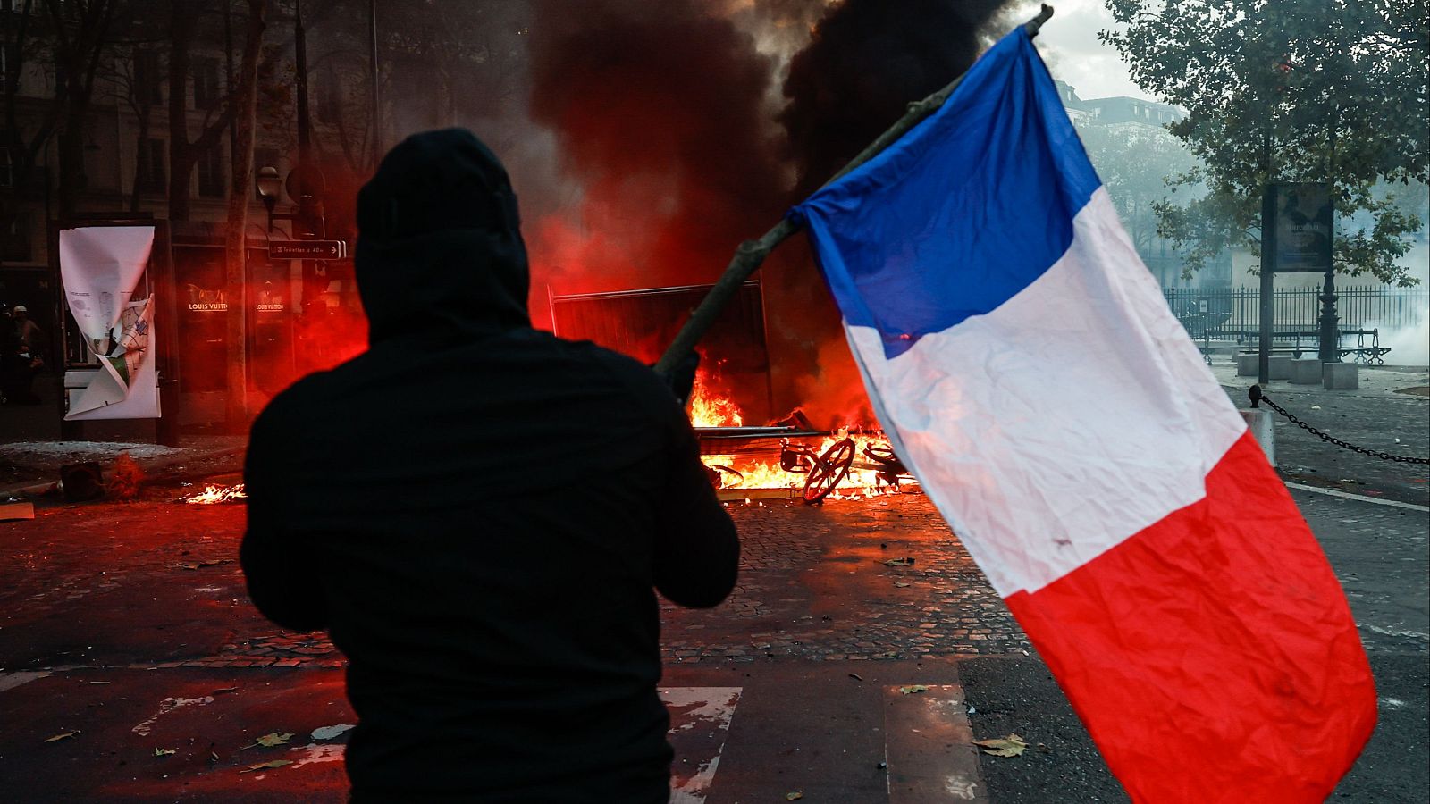 Un manifestante que porta una bandera francesa se enfrenta a la policía en París