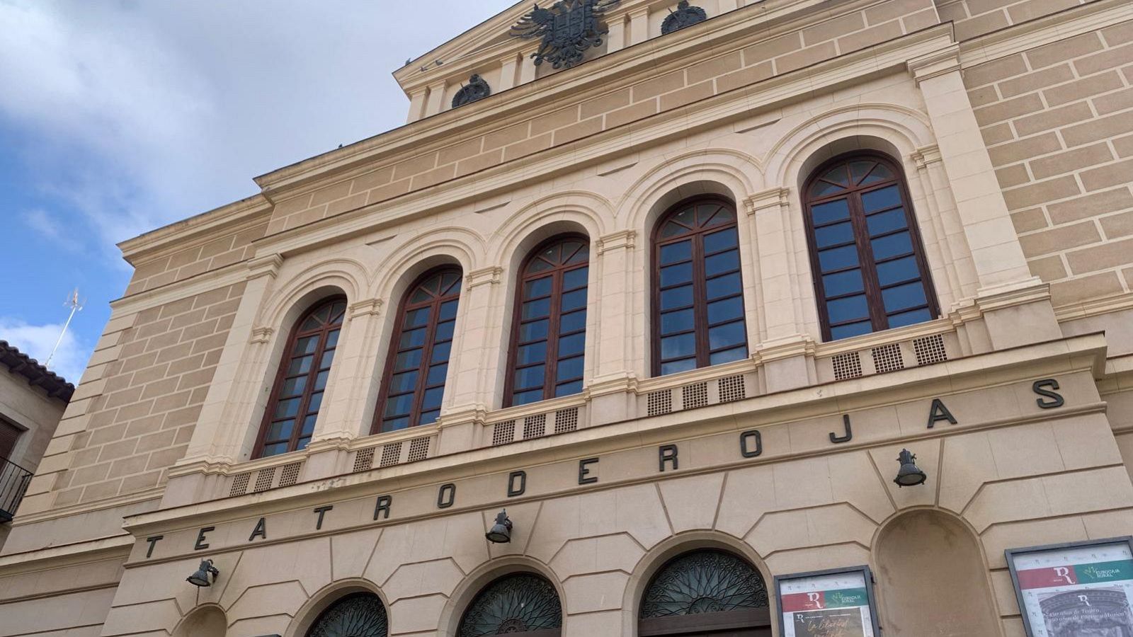 Fachada clásica en tono arena del Teatro de Rojas en Toledo, destacando sus arcos, ventanales y el rótulo metálico bajo un cielo nublado.