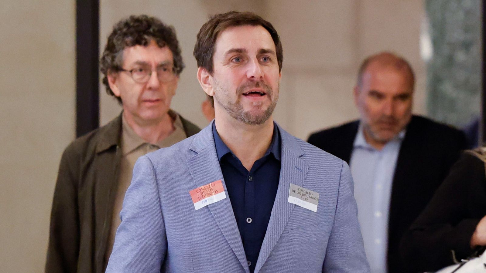 Antoni Comín camina seriós per un edifici institucional amb acreditacions del Congrés, acompanyat pel seu advocat Gonzalo Boye.