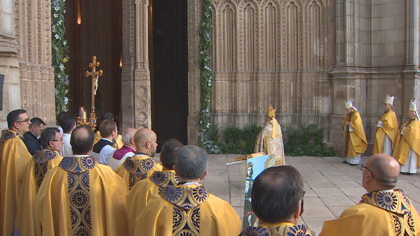 Ceremonia litúrgica católica al aire libre ante la fachada gótica de una catedral, con sacerdotes y obispos ataviados con vestimentas doradas y mitras.