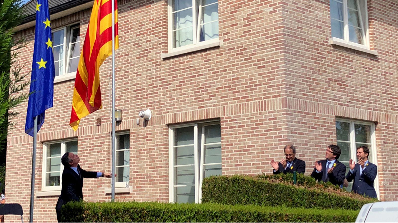 Torra, Puigdemont y Toni Comín aplauden el izado de bandera en la casa de Waterloo
