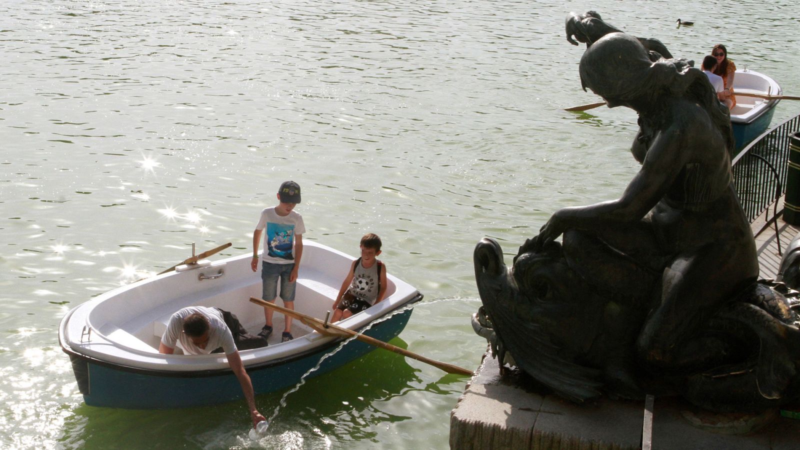 Un padre se refresca con sus hijos esta tarde en el parque de El Retiro de Madrid.