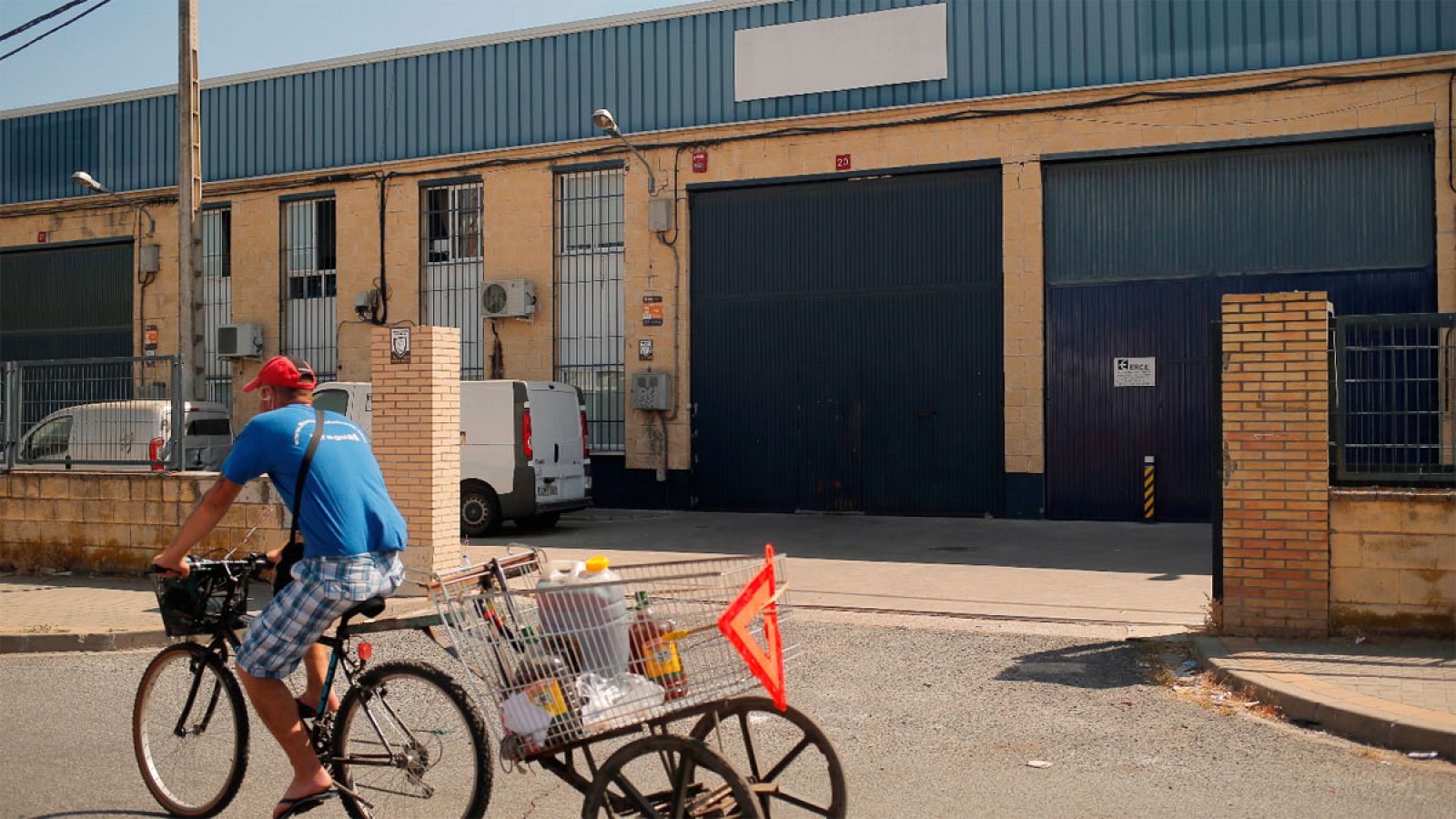 Un joven pasa en bicicleta frente a la empresa Magrudis en Sevilla
