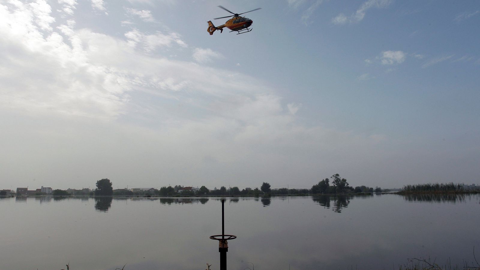 Gota fría: Un helicóptero busca en la zona donde el hombre desaparecido fue arrastrado por el agua en Dolores, Alicante.