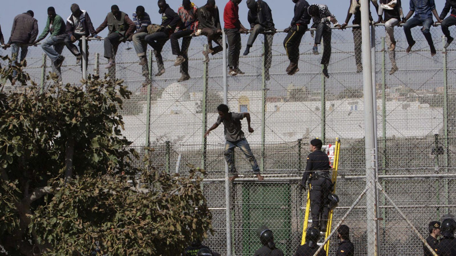 Un grupo de migrantes subsaharianos encaramados a la valla de Melilla en 2015