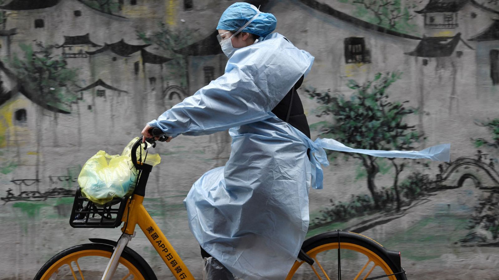 Una mujer montando en bicicleta por una calle de Wuhan, China.
