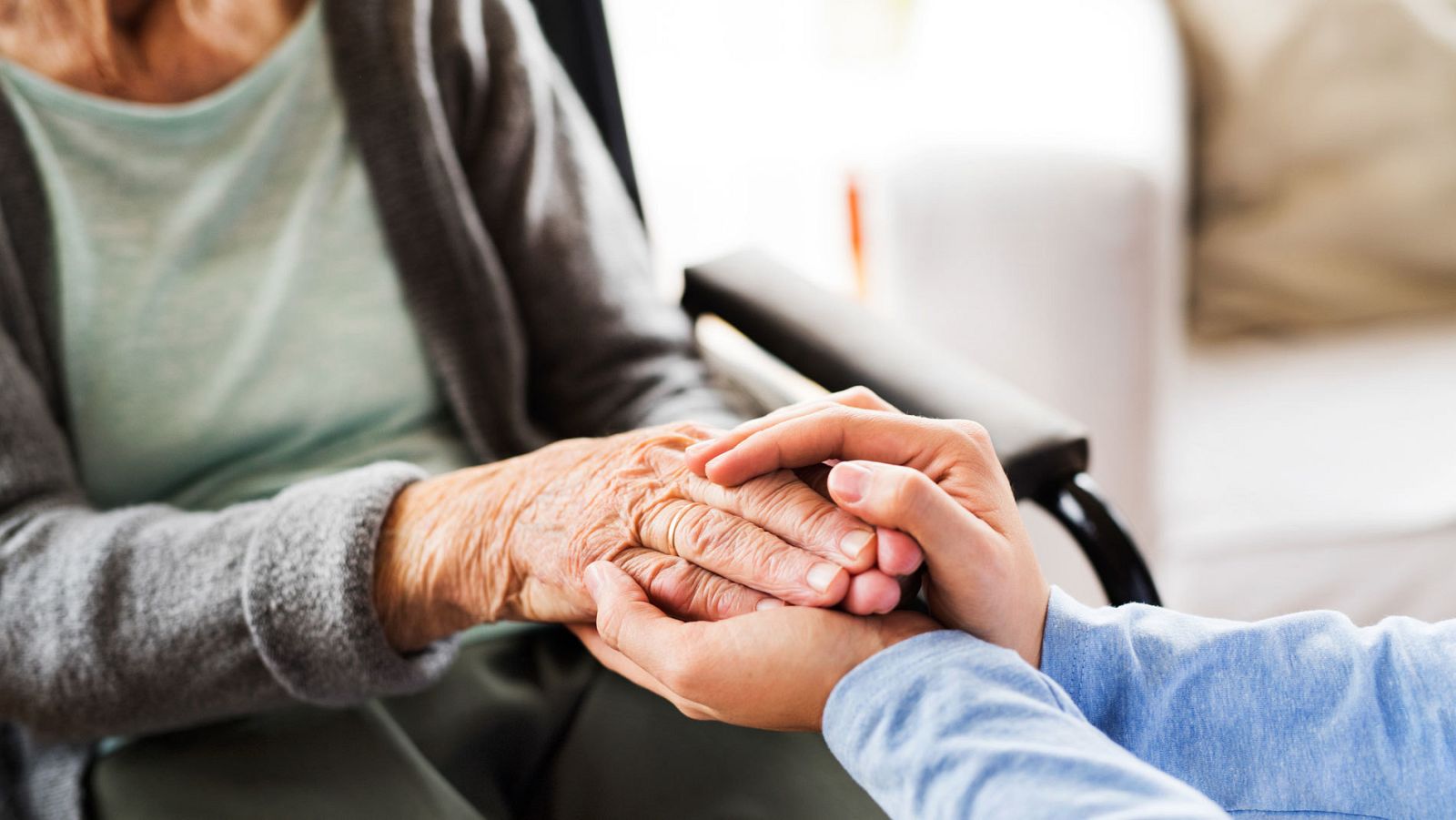 Un asistente asnitario sostiene las manos de una mujer dependiente