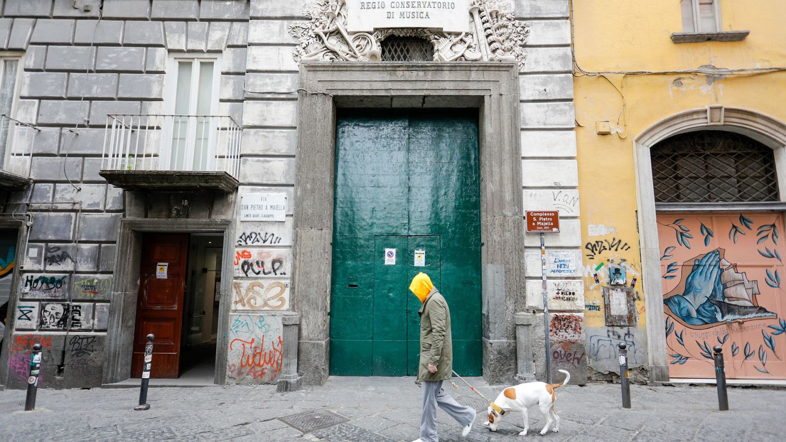 Joven italiano y su perro paseando por una calle solitaria de Nápoles este viernes por la mañana.