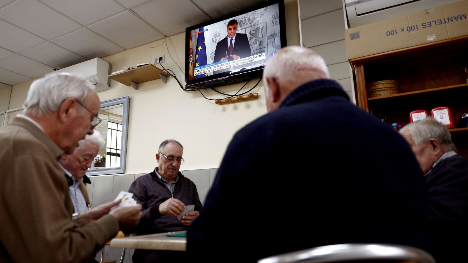Un grupo de ancianos juega a las cartas en un bar del barrio de Aluche, en Madrid