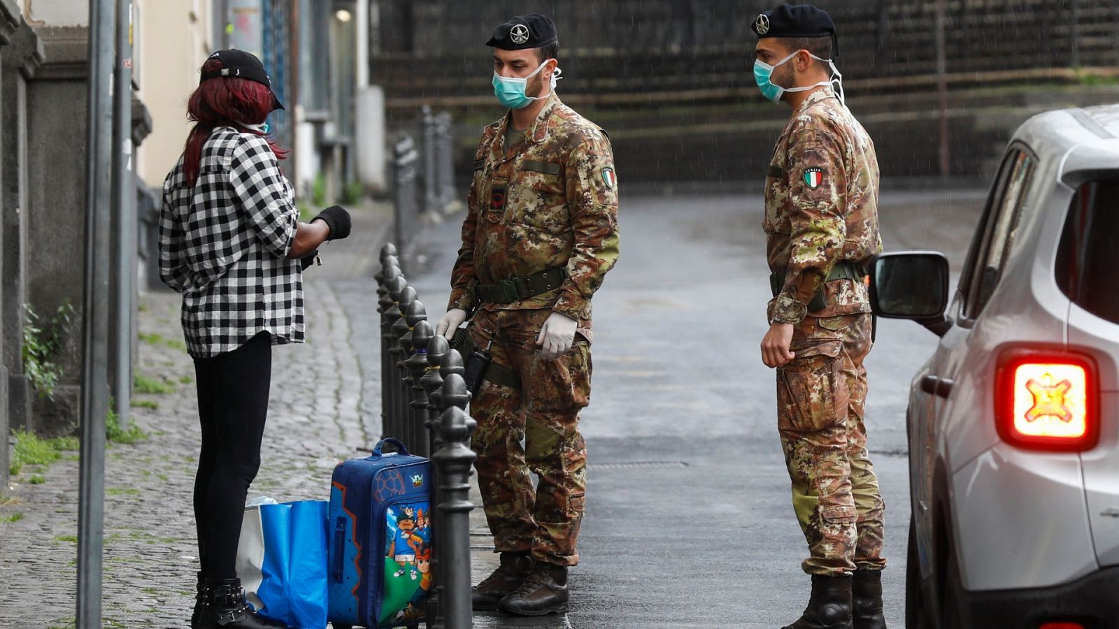 Soldados italianos piden su identificación a una viandante en Catania.
