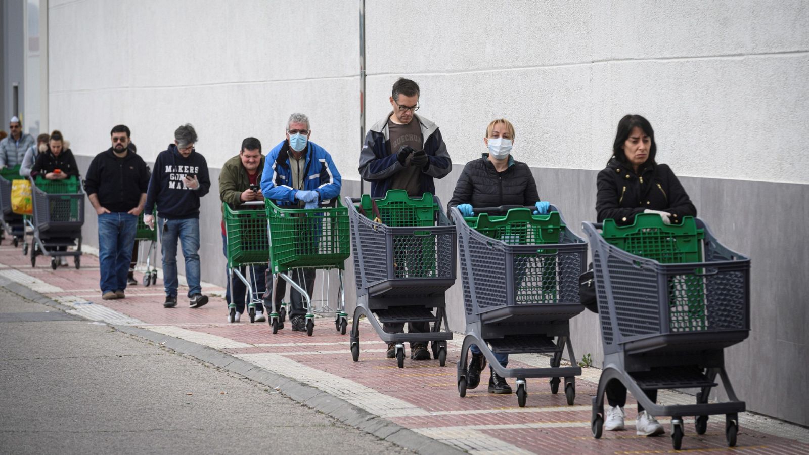 Varias personas esperando turno para hacer la compra en Alcalá de Henares