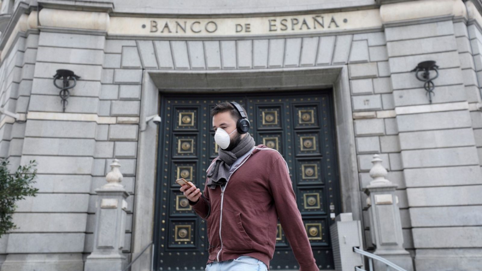 Un hombre camina con mascarilla frente al Banco de España en Madrid