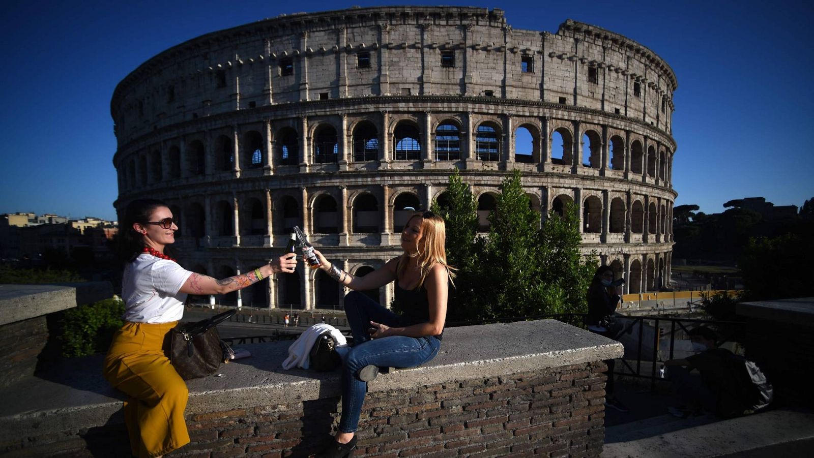 Dos mujeres brindan frente al Coliseo de Roma, tras relajarse las medidas de confinamiento por el coronavirus en Italia