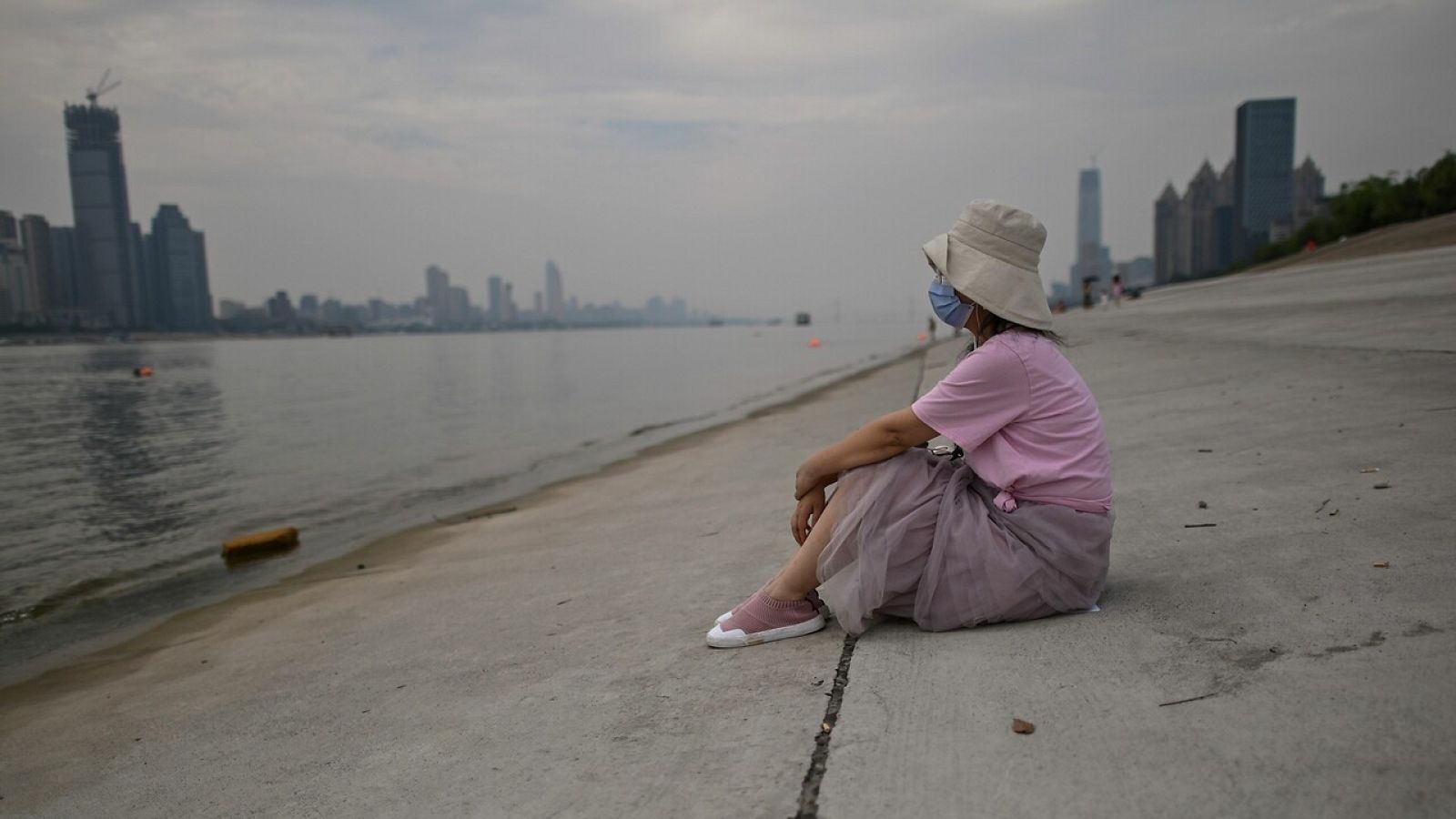 Una mujer con mascarilla en la orilla del río Yangtsé, Wuhan
