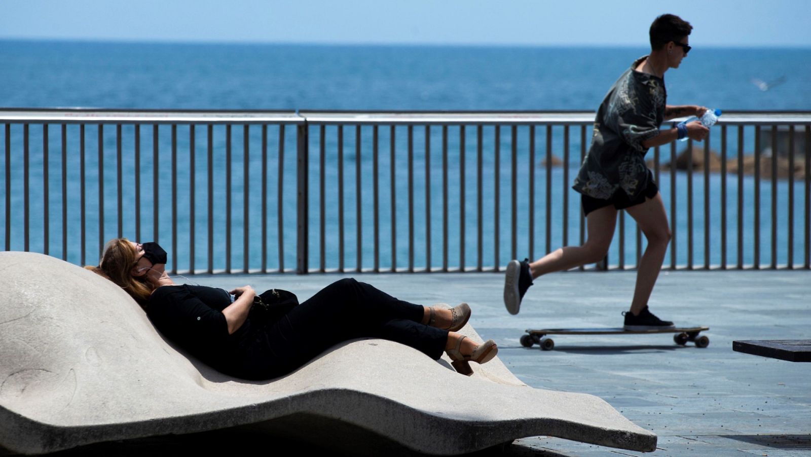 Una mujer toma el sol en el paseo marítimo de la Barceloneta