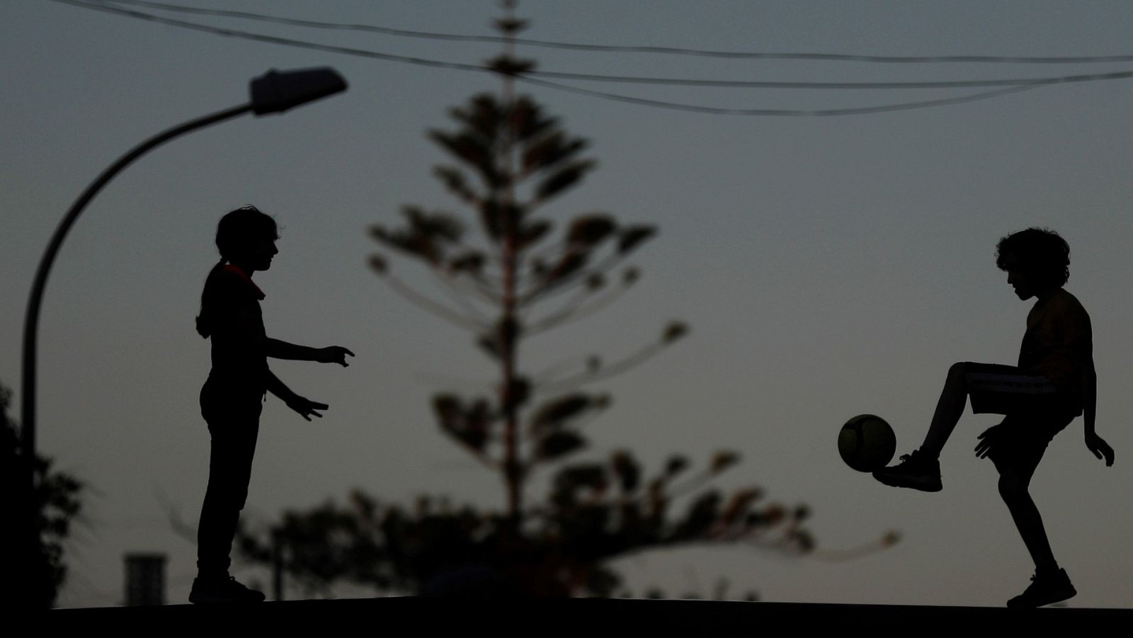 Dos niños juegan a la pelota al atardecer durante el tercer día de apertura para los menores de 14 años en Godella (Valencia).